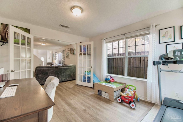 interior space featuring a healthy amount of sunlight, visible vents, wood finished floors, and french doors