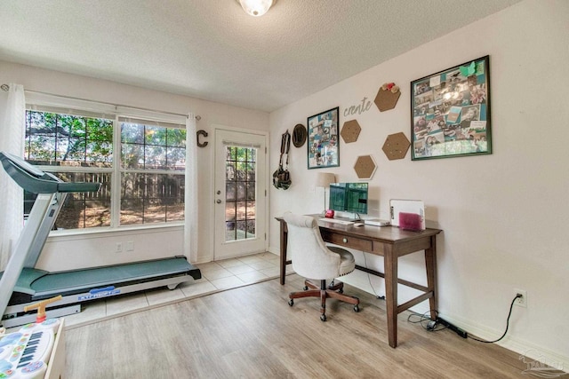 home office featuring a textured ceiling, plenty of natural light, baseboards, and light wood-style floors