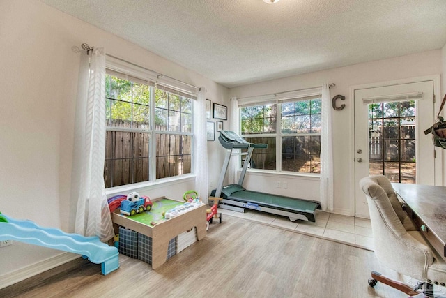 exercise area with a textured ceiling, wood finished floors, and a healthy amount of sunlight