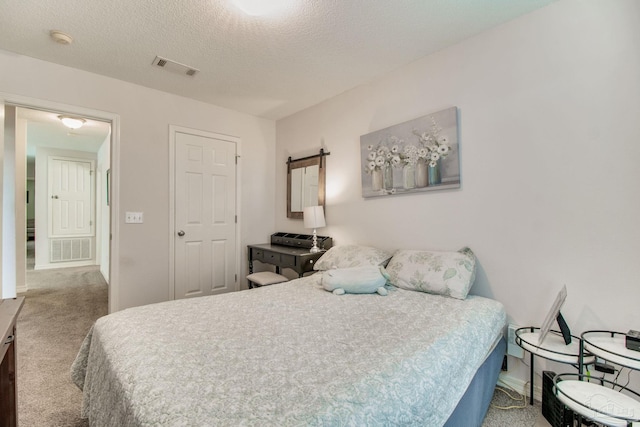 bedroom featuring light carpet, a textured ceiling, and visible vents