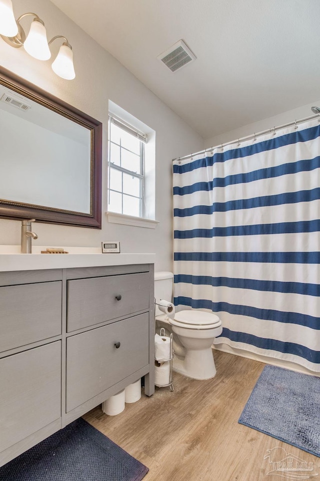 bathroom featuring visible vents, toilet, a shower with curtain, wood finished floors, and vanity