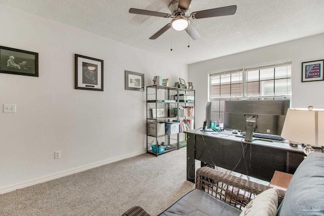 office space with a ceiling fan, baseboards, a textured ceiling, and light colored carpet