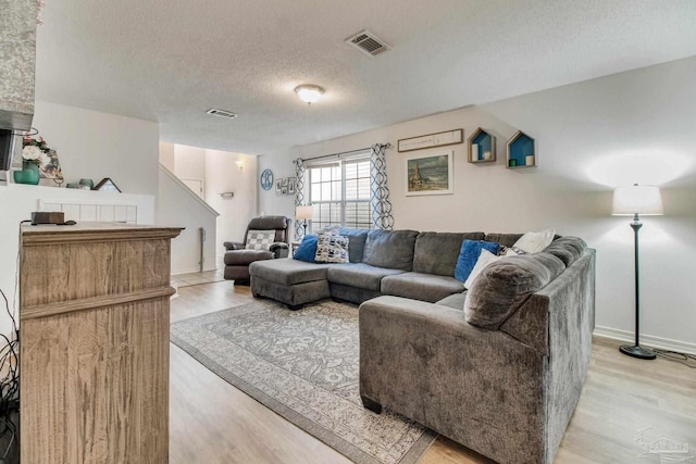 living area with visible vents, a textured ceiling, and light wood finished floors