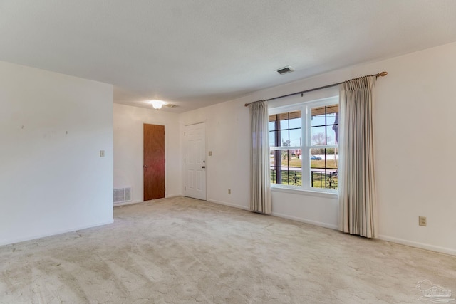 spare room with a textured ceiling, carpet floors, visible vents, and baseboards