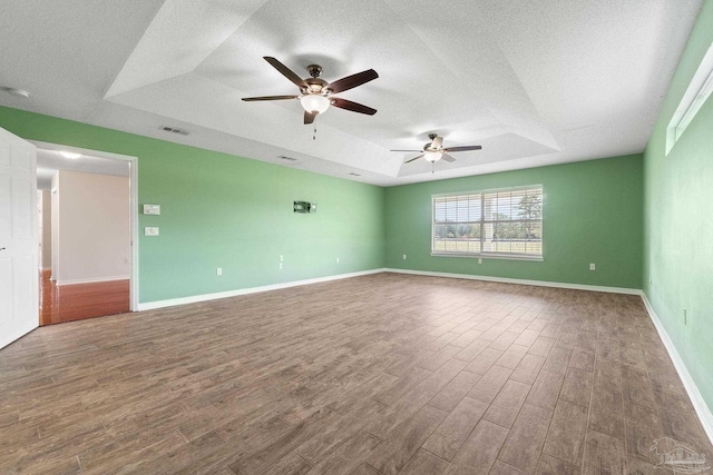 spare room featuring a textured ceiling, a tray ceiling, hardwood / wood-style floors, and ceiling fan