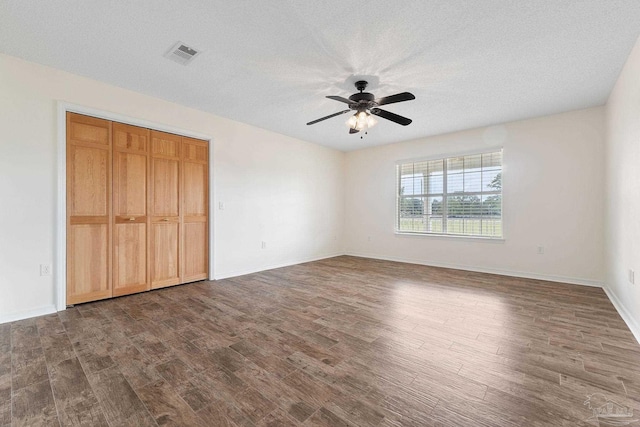 unfurnished bedroom with a textured ceiling, dark wood-type flooring, ceiling fan, and a closet