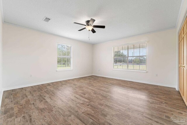 spare room featuring a textured ceiling, crown molding, dark hardwood / wood-style floors, and ceiling fan