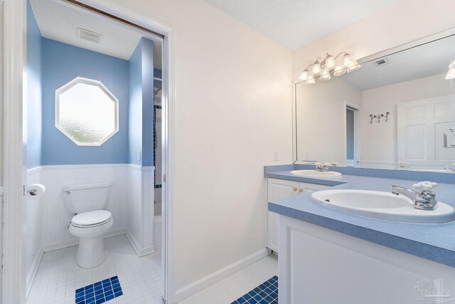 bathroom featuring a textured ceiling, vanity, toilet, and tile patterned floors