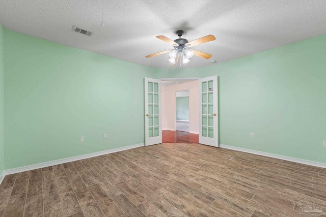 empty room featuring hardwood / wood-style floors, ceiling fan, french doors, and a textured ceiling