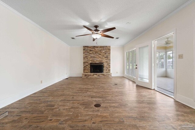 unfurnished living room featuring a stone fireplace, dark hardwood / wood-style flooring, a textured ceiling, ceiling fan, and ornamental molding