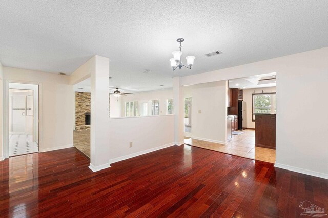 interior space with ceiling fan with notable chandelier, a textured ceiling, hardwood / wood-style flooring, and a fireplace