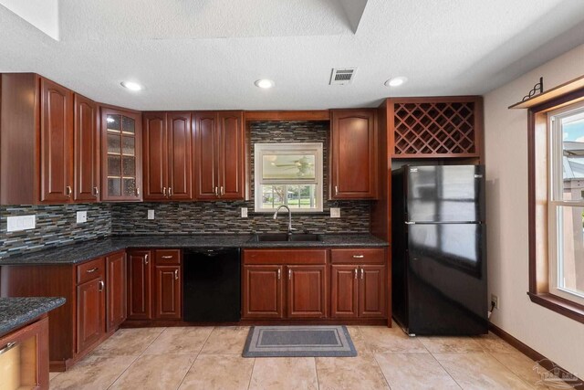 kitchen with a textured ceiling, black appliances, decorative backsplash, and sink