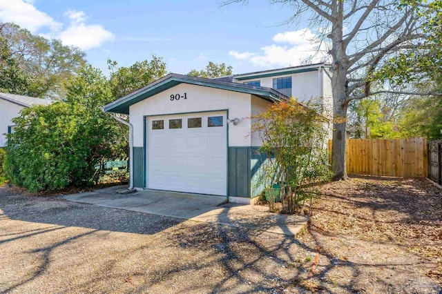 garage featuring concrete driveway and fence