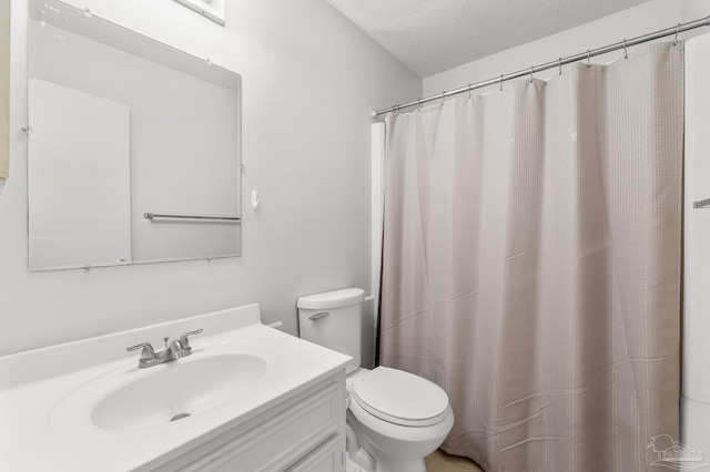 full bathroom featuring curtained shower, vanity, toilet, and a textured ceiling