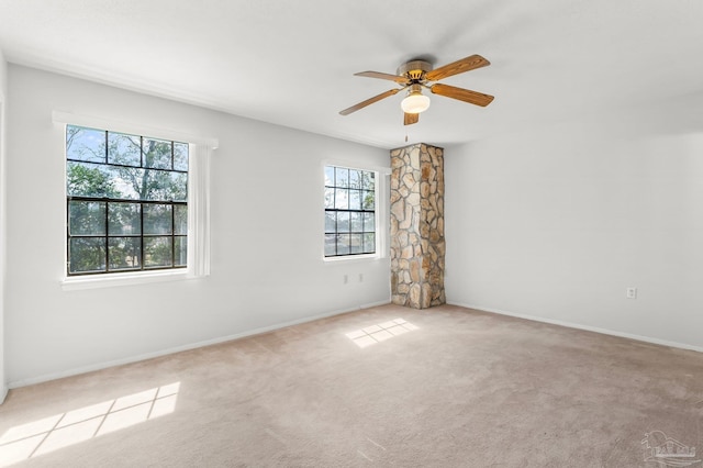 carpeted empty room with a ceiling fan and baseboards