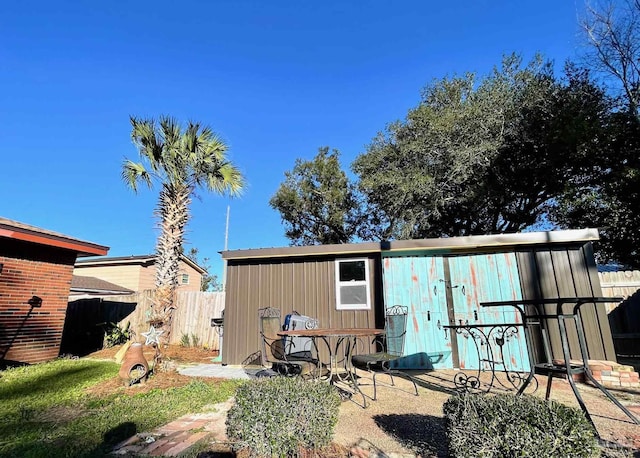 view of outbuilding featuring fence and an outbuilding