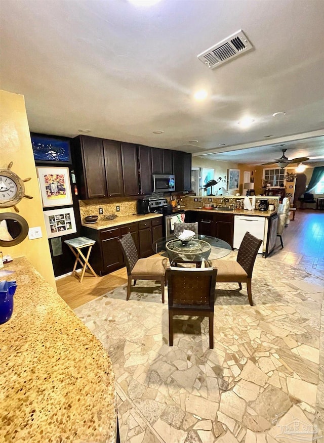 kitchen with visible vents, ceiling fan, a peninsula, stainless steel appliances, and dark brown cabinets