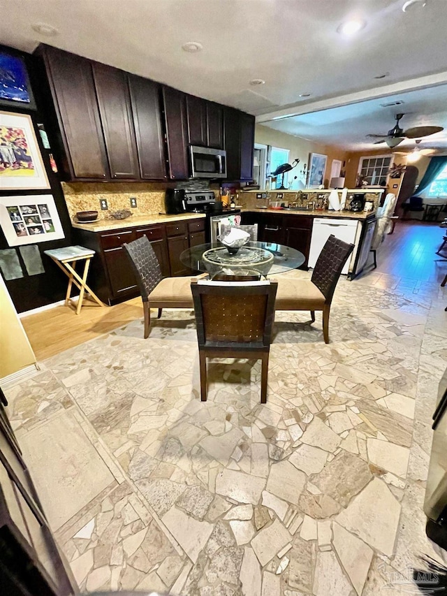 kitchen with ceiling fan, dark brown cabinetry, stainless steel appliances, light countertops, and decorative backsplash