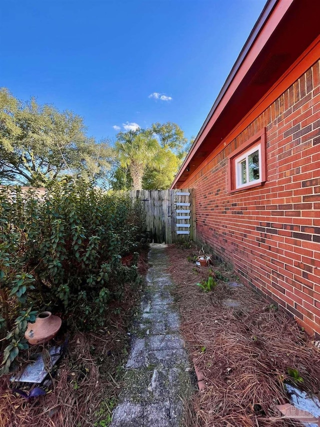 view of home's exterior featuring brick siding and fence