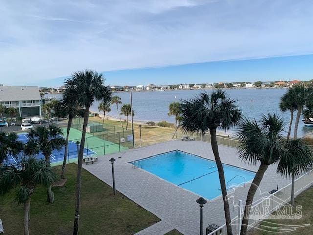 pool featuring a water view, fence, and a lawn