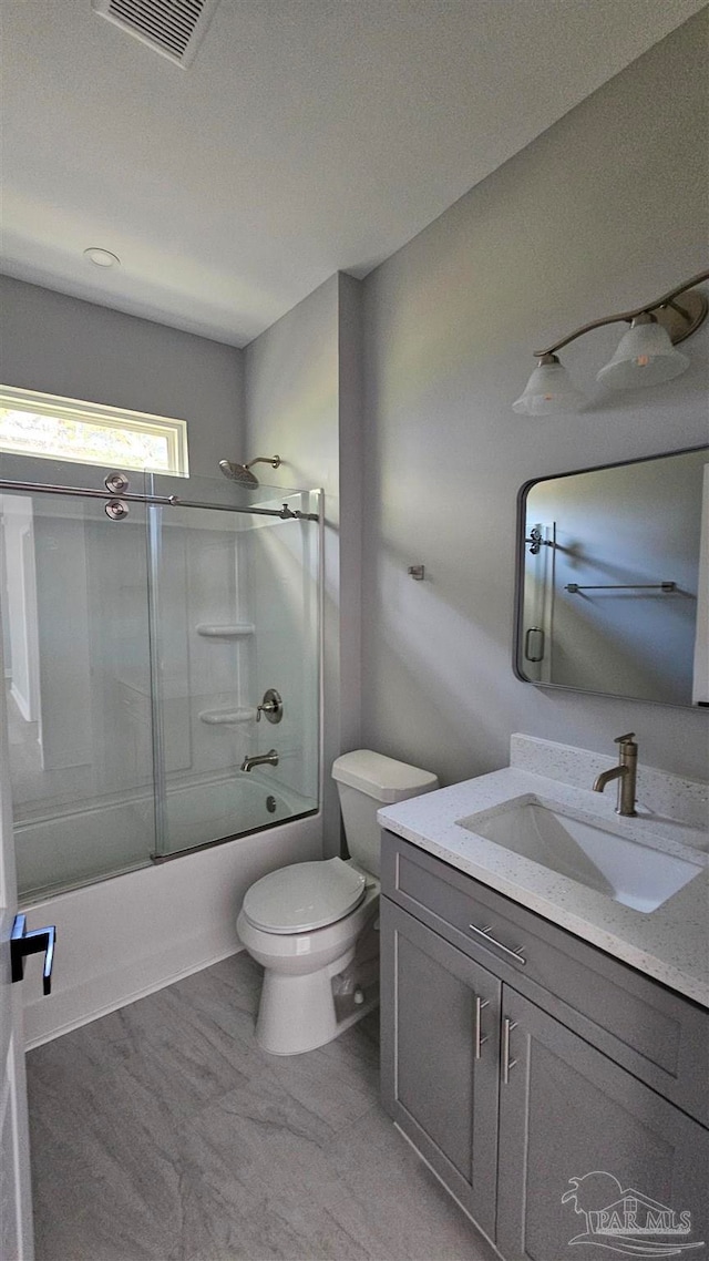 full bathroom with vanity, bath / shower combo with glass door, and toilet