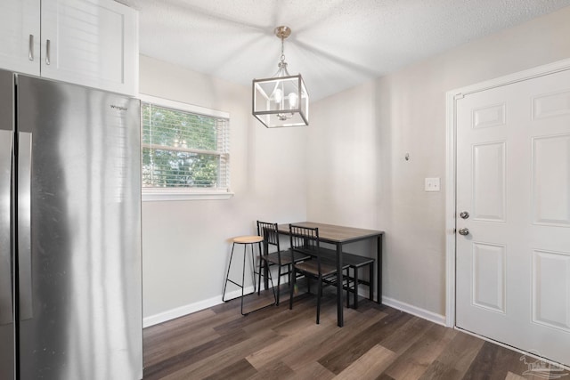 dining area with dark wood-type flooring, a chandelier, and a textured ceiling