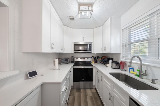 kitchen featuring appliances with stainless steel finishes, decorative backsplash, dark hardwood / wood-style flooring, white cabinets, and sink