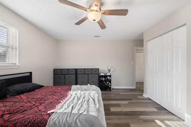 bedroom with ceiling fan, a textured ceiling, and dark hardwood / wood-style flooring