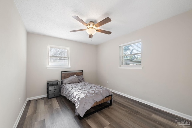 bedroom featuring ceiling fan, wood-type flooring, multiple windows, and a textured ceiling