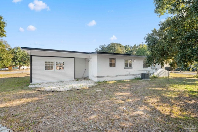 back of house with central AC unit and a lawn