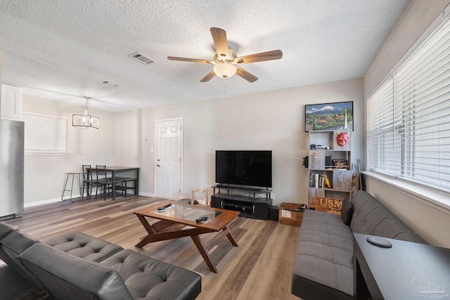 living room featuring hardwood / wood-style flooring, a textured ceiling, and ceiling fan with notable chandelier