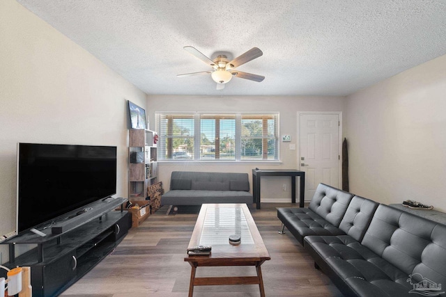 living room featuring ceiling fan, dark hardwood / wood-style flooring, and a textured ceiling