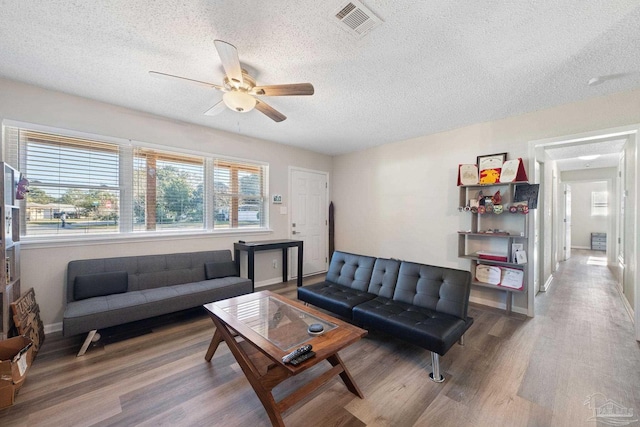 living room featuring a textured ceiling, ceiling fan, and hardwood / wood-style flooring