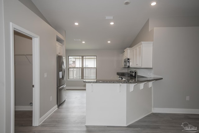 3620 Ranch Dr, Crestview, FL 32539 - kitchen featuring appliances with stainless steel finishes, a peninsula, dark stone countertops, a breakfast bar, and white cabinetry