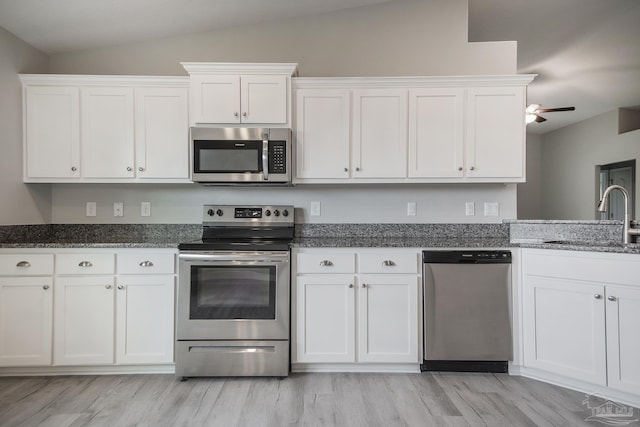 3620 Ranch Dr, Crestview, FL 32539 - kitchen featuring appliances with stainless steel finishes, a sink, lofted ceiling, white cabinetry, and dark stone countertops
