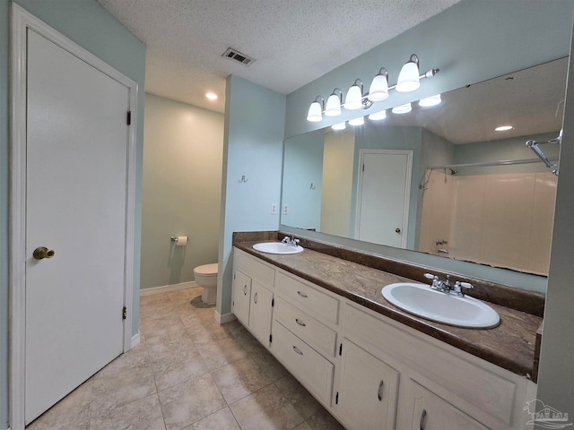 bathroom with a textured ceiling, toilet, vanity, a shower, and tile patterned flooring