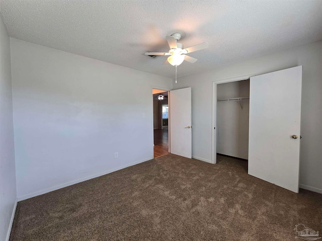 unfurnished bedroom with dark carpet, a textured ceiling, a closet, and ceiling fan