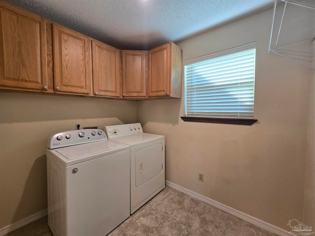 clothes washing area featuring a textured ceiling, separate washer and dryer, and cabinets