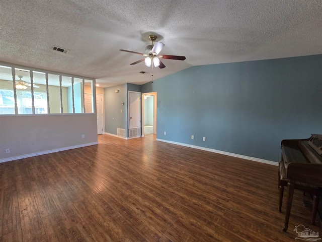 interior space featuring a textured ceiling, ceiling fan, dark wood-type flooring, and vaulted ceiling