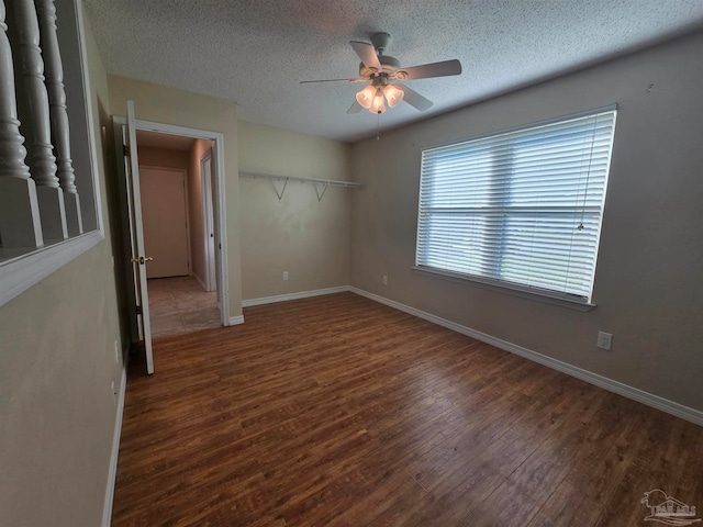 empty room with dark hardwood / wood-style floors, a textured ceiling, and ceiling fan