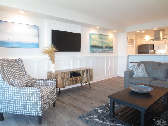 living area with dark wood-style floors, recessed lighting, wainscoting, and a decorative wall