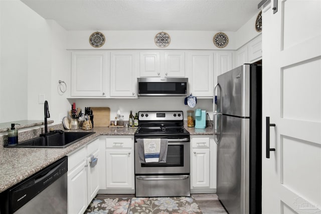 kitchen with light stone counters, sink, stainless steel appliances, and white cabinets