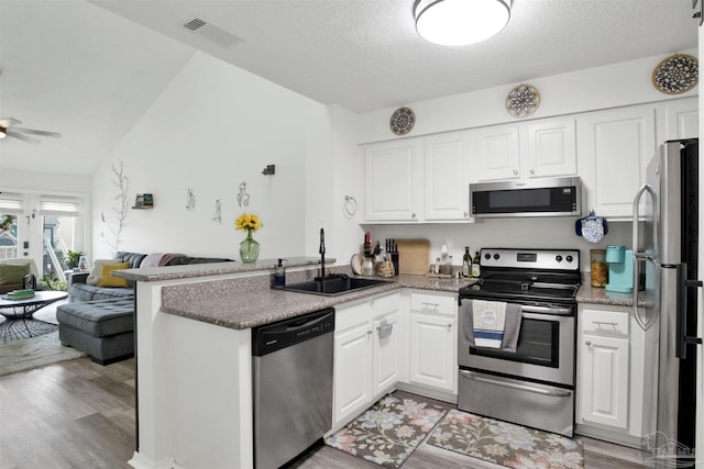 kitchen with sink, white cabinetry, light wood-type flooring, appliances with stainless steel finishes, and kitchen peninsula