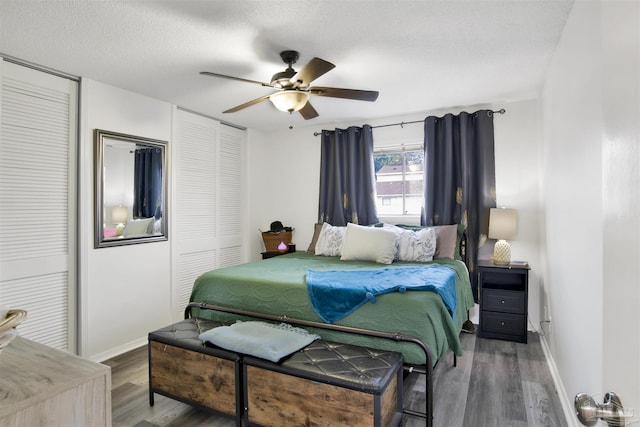 bedroom featuring multiple closets, ceiling fan, hardwood / wood-style floors, and a textured ceiling