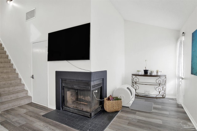 living room with a multi sided fireplace, vaulted ceiling, and hardwood / wood-style floors