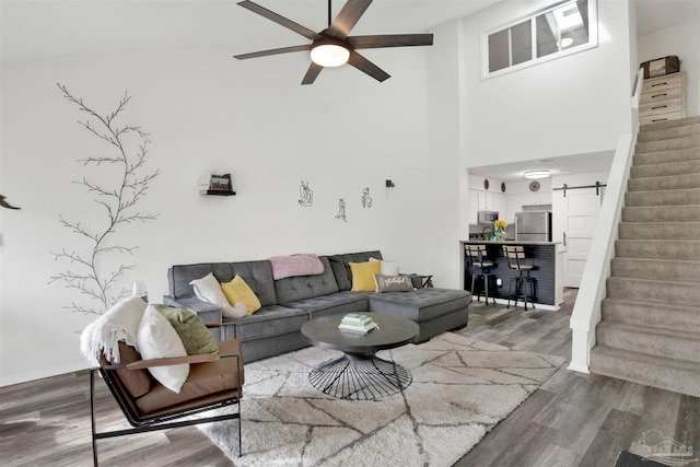 living room with a towering ceiling, hardwood / wood-style floors, and ceiling fan