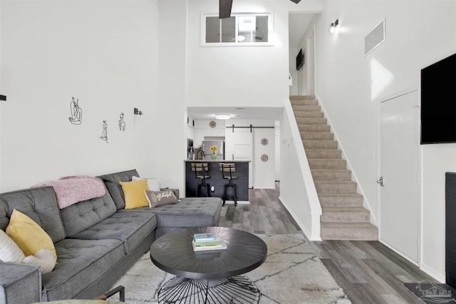 living room featuring a high ceiling, wood-type flooring, and a barn door