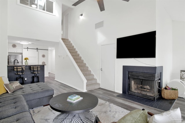 living room featuring hardwood / wood-style flooring, a barn door, a towering ceiling, and ceiling fan