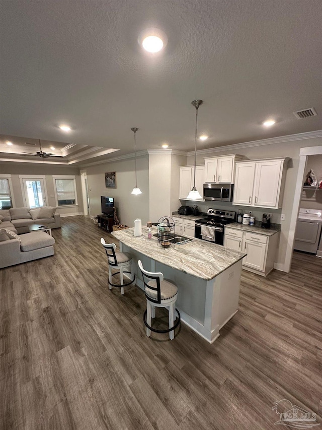 kitchen with open floor plan, a kitchen bar, appliances with stainless steel finishes, white cabinets, and a sink