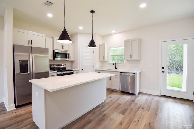 5742 San Blas St, Milton, FL 32583 - kitchen featuring stainless steel appliances, a sink, a kitchen island, light wood-style flooring, and light countertops